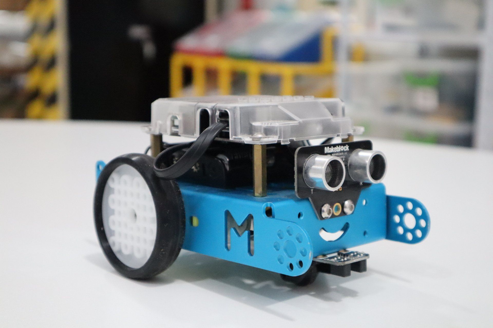 a blue robot with the letter m on it is sitting on a table .