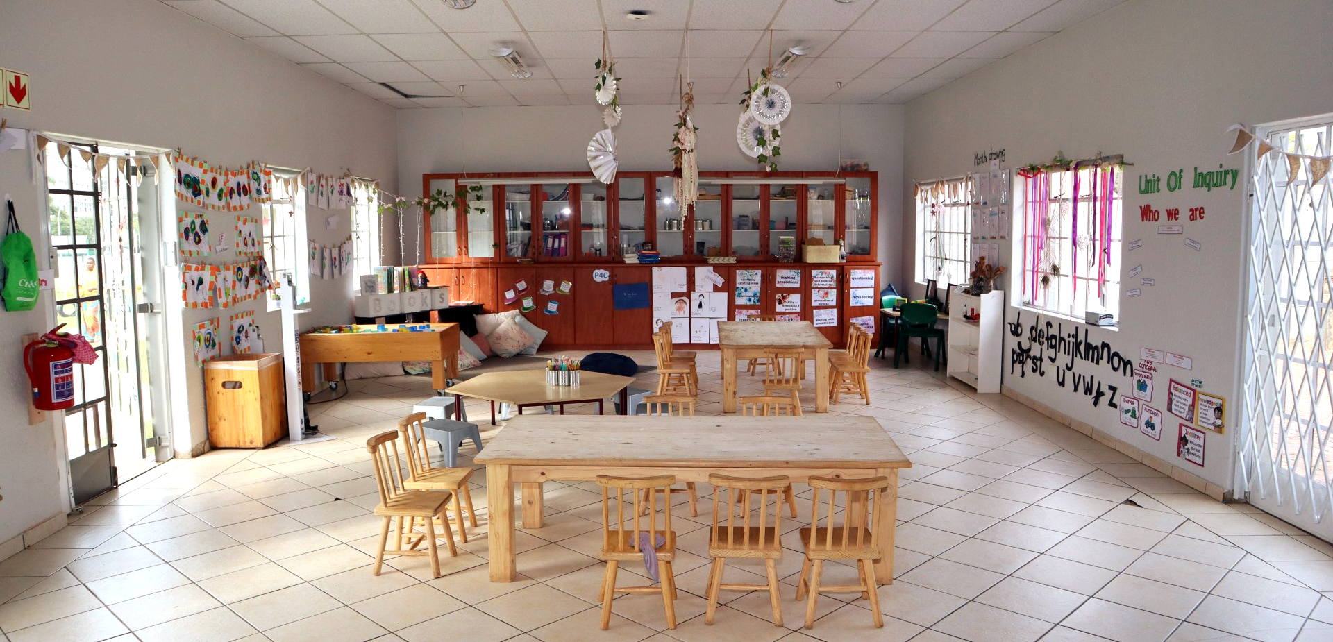 a classroom with tables and chairs and a bulletin board