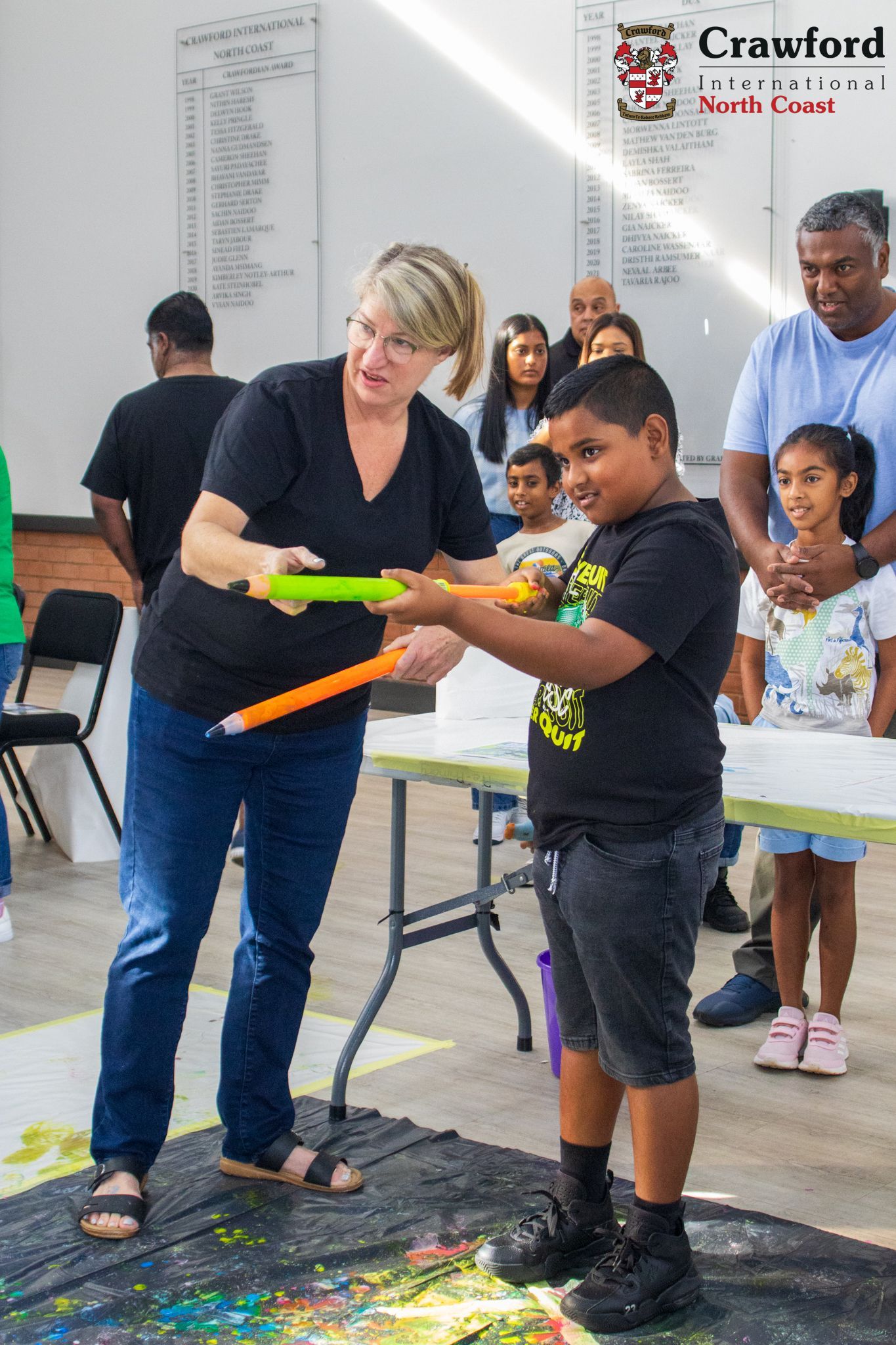 A woman is helping a young boy with a painting.