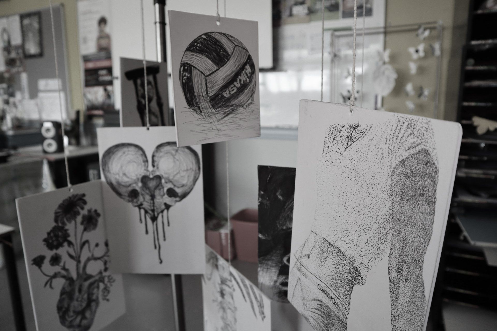 a bunch of black and white drawings are hanging from the ceiling