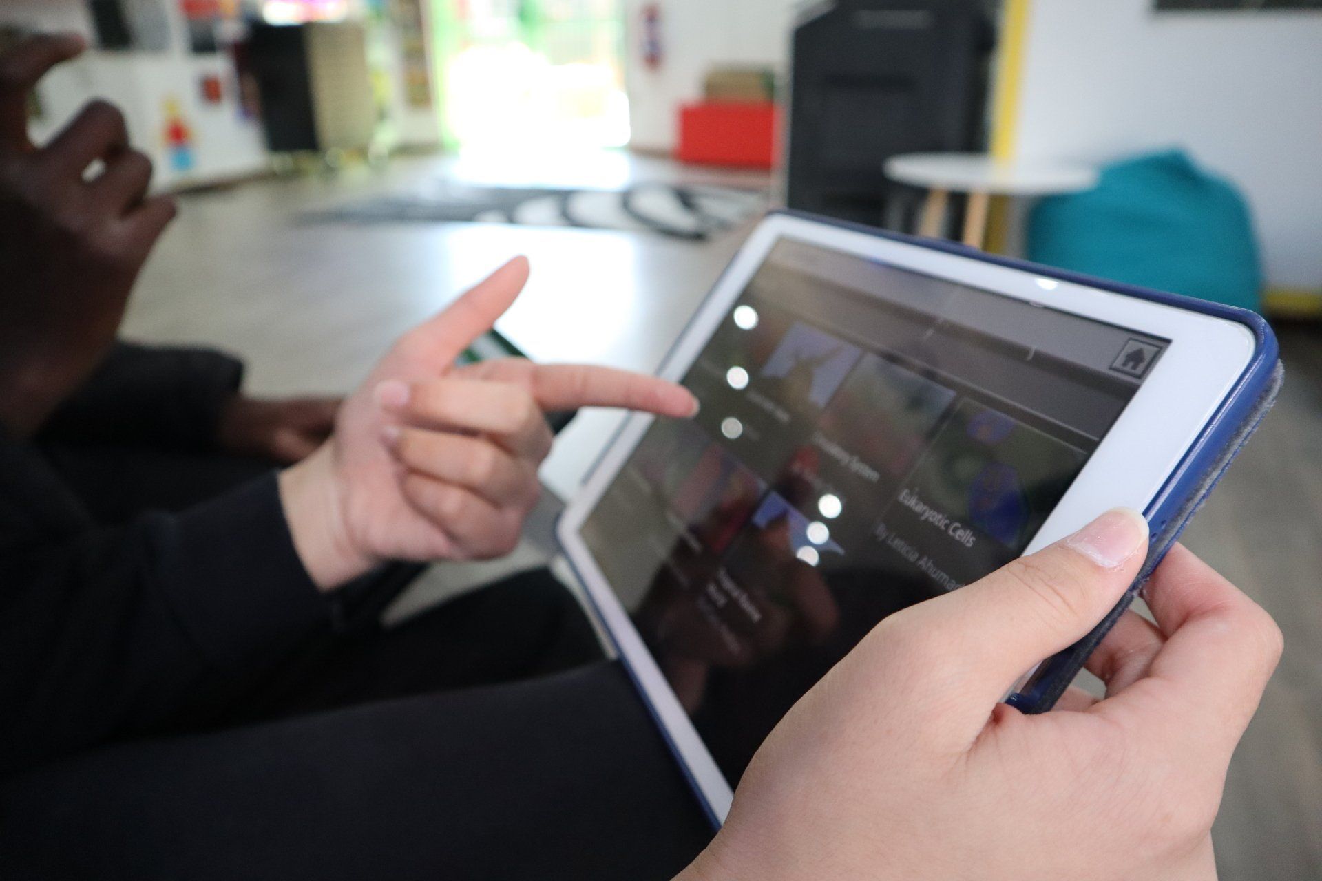 a person is holding a tablet and pointing at the screen .