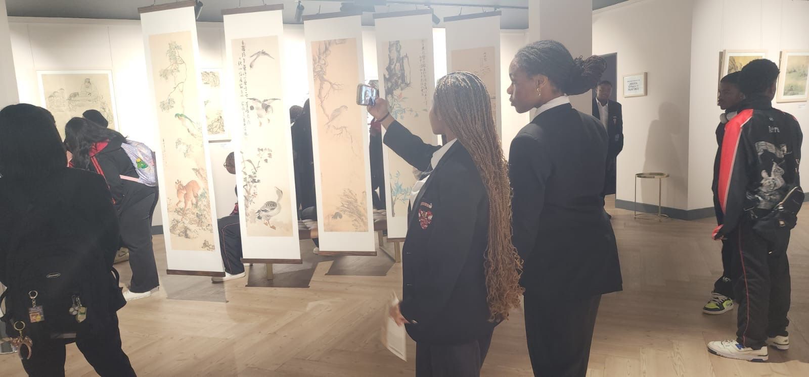 A group of people are looking at paintings in a museum.