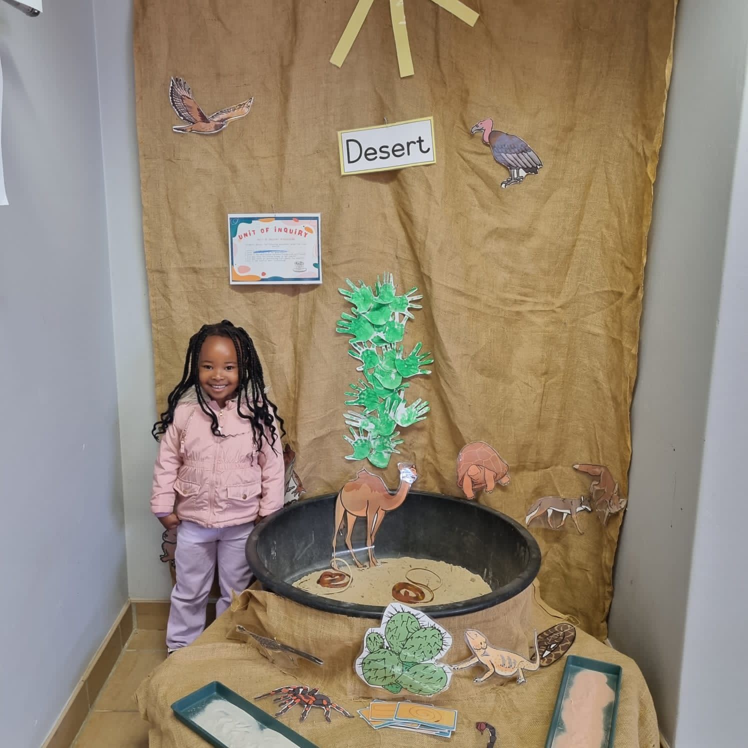 A little girl is standing in front of a desert scene