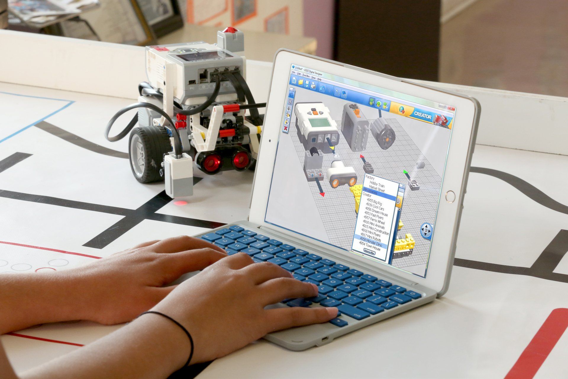 a person is typing on a laptop with a robot in the background .
