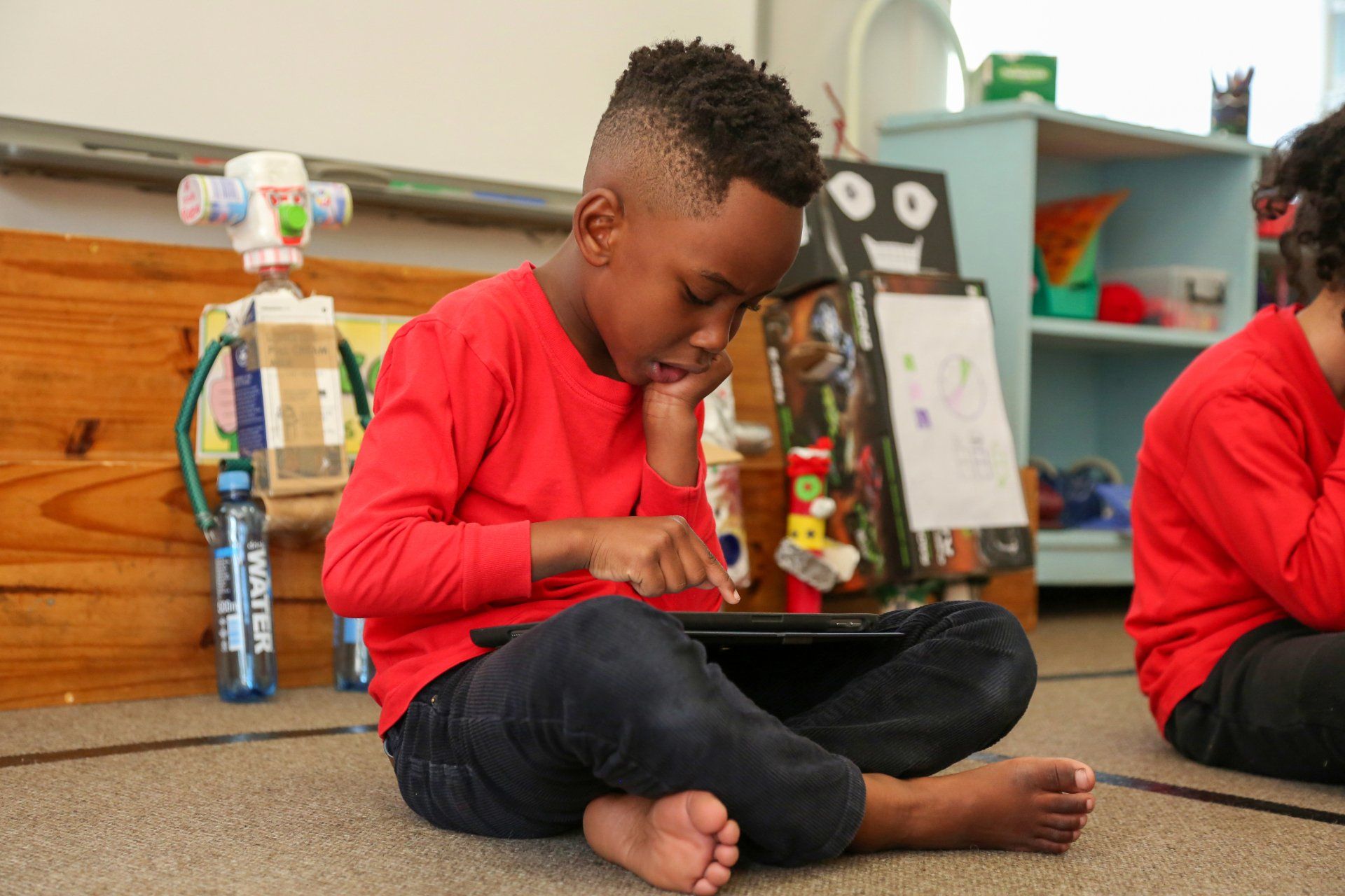 a young boy is sitting on the floor using a laptop computer .