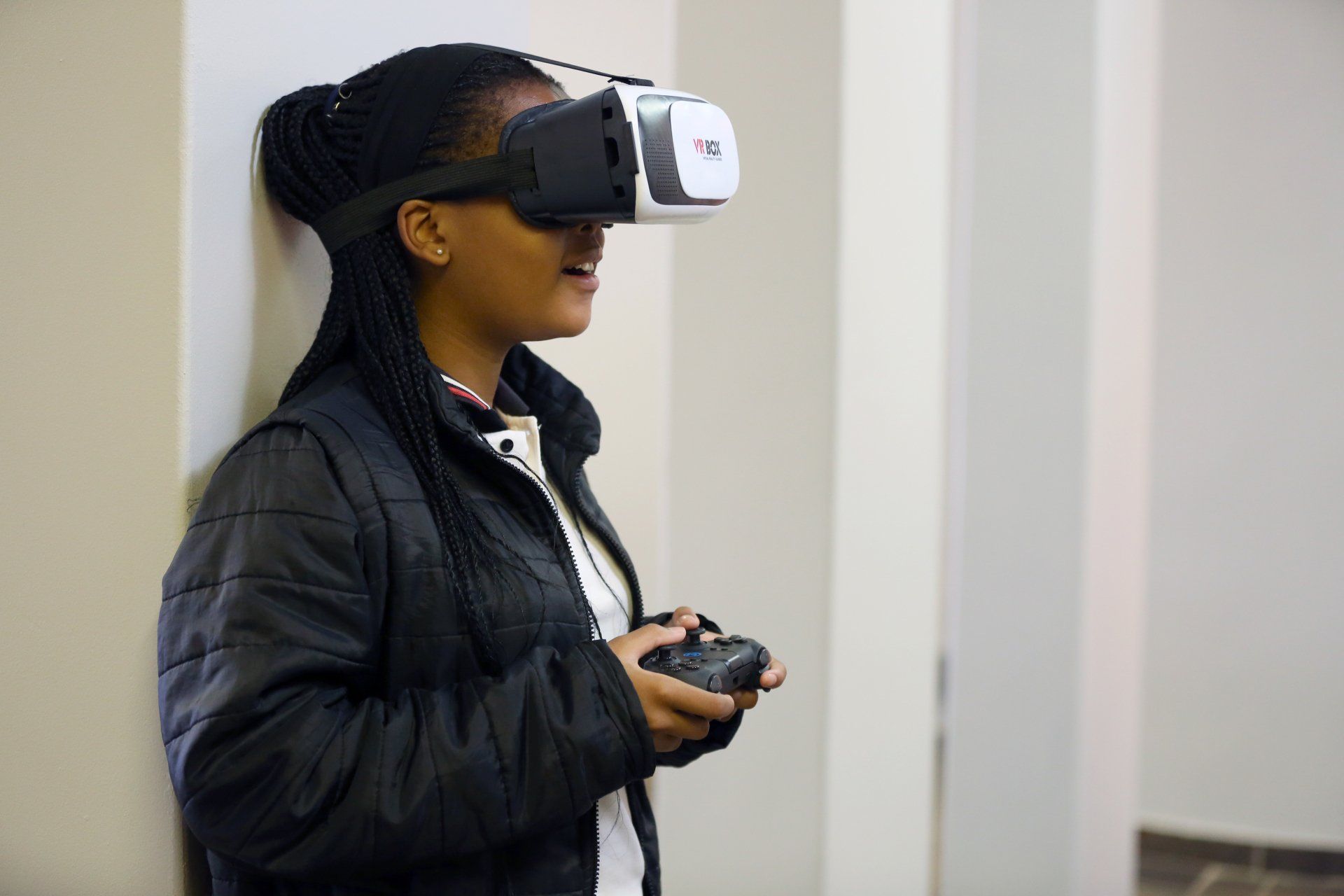 a girl is wearing a virtual reality headset and holding a remote control .