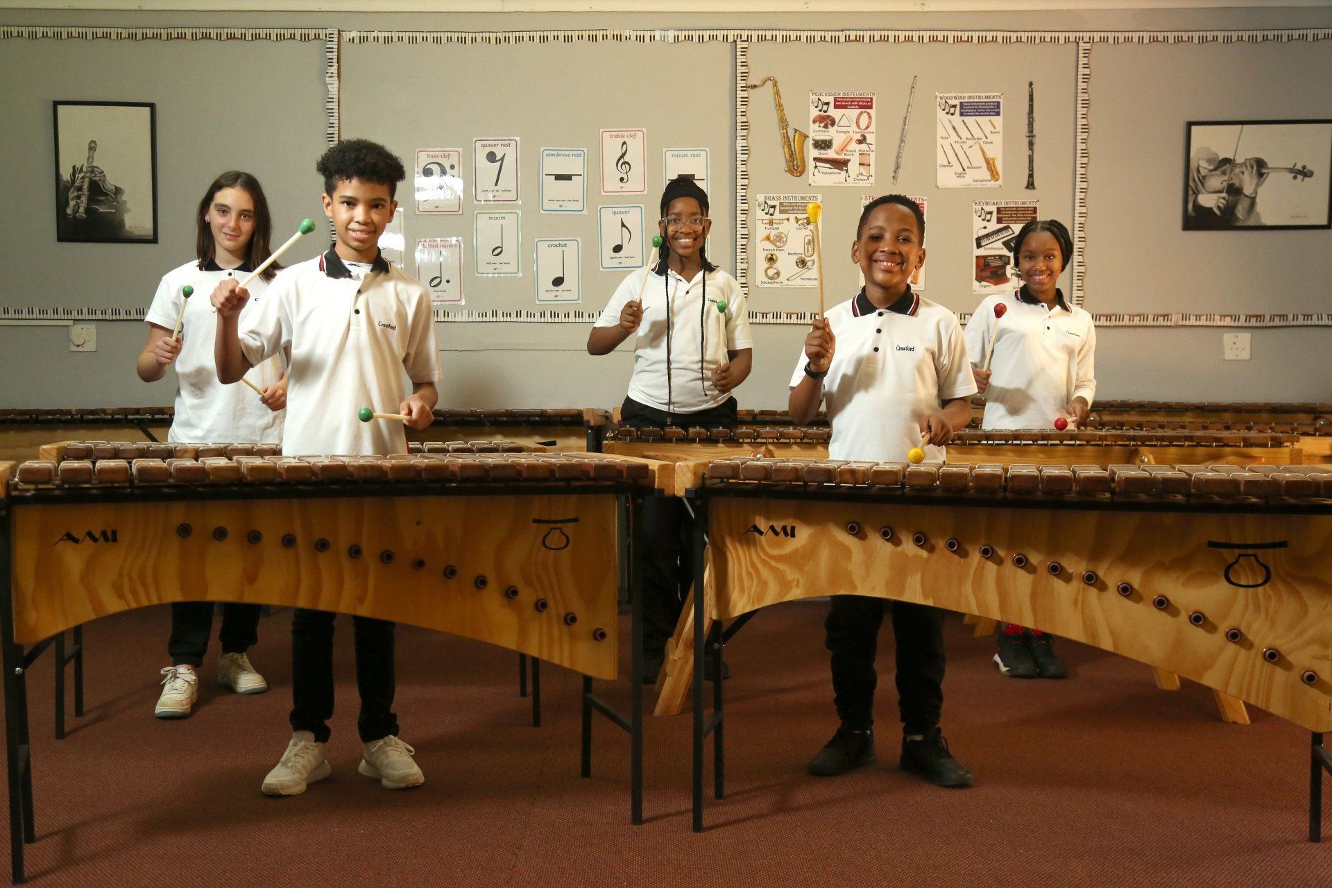 A group of children are playing marimbas in a classroom.
