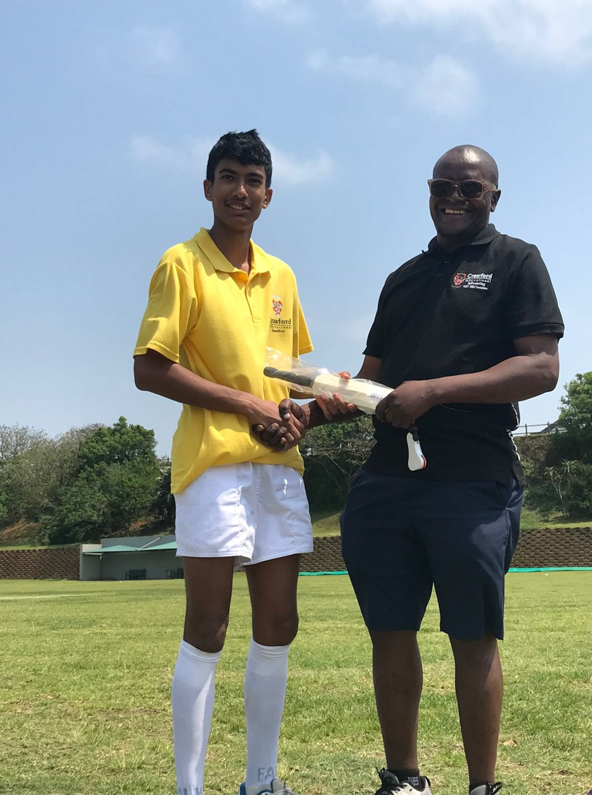 A man is giving a certificate to a young boy on a field.