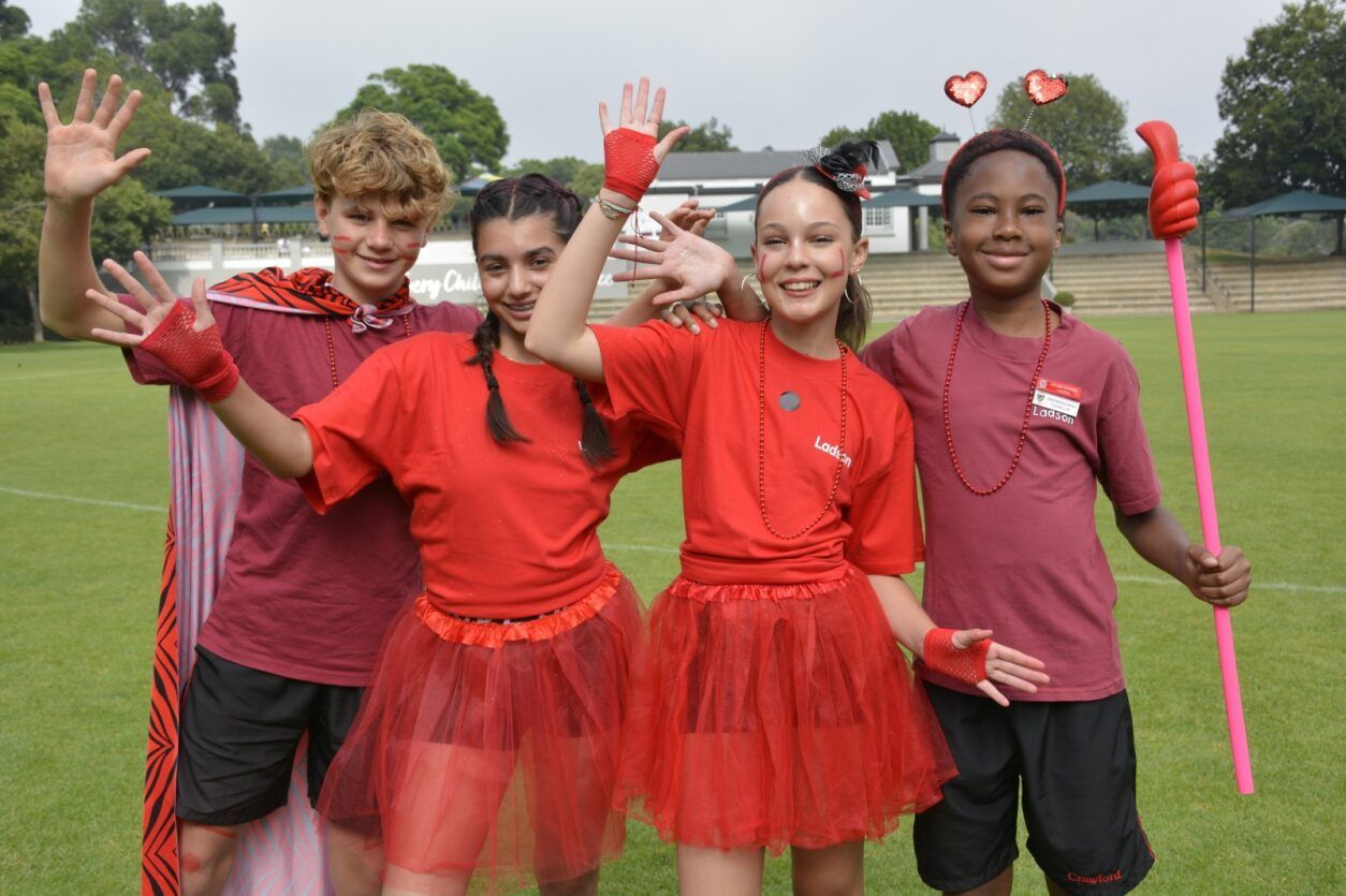 A group of children dressed in red are posing for a picture on a field.