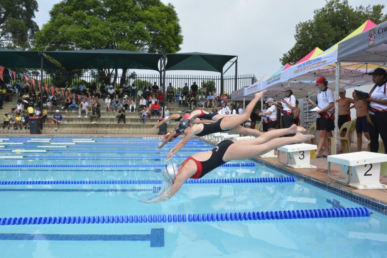 A group of people are diving into a swimming pool.