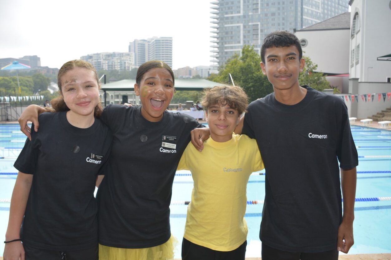 A group of young people are posing for a picture in front of a swimming pool.