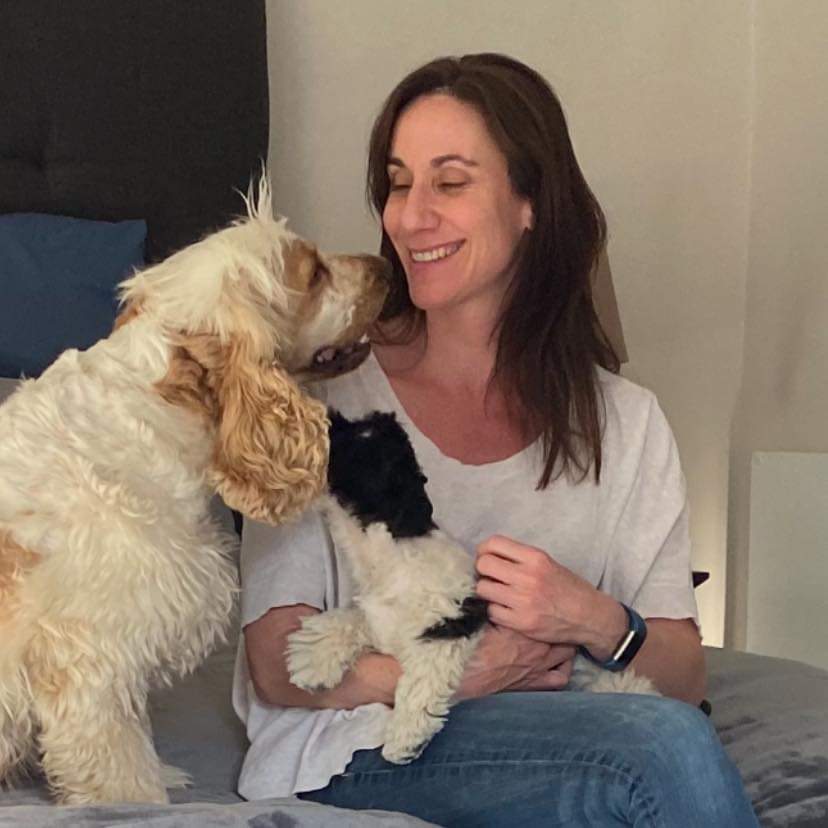 A woman is sitting on a bed with two dogs