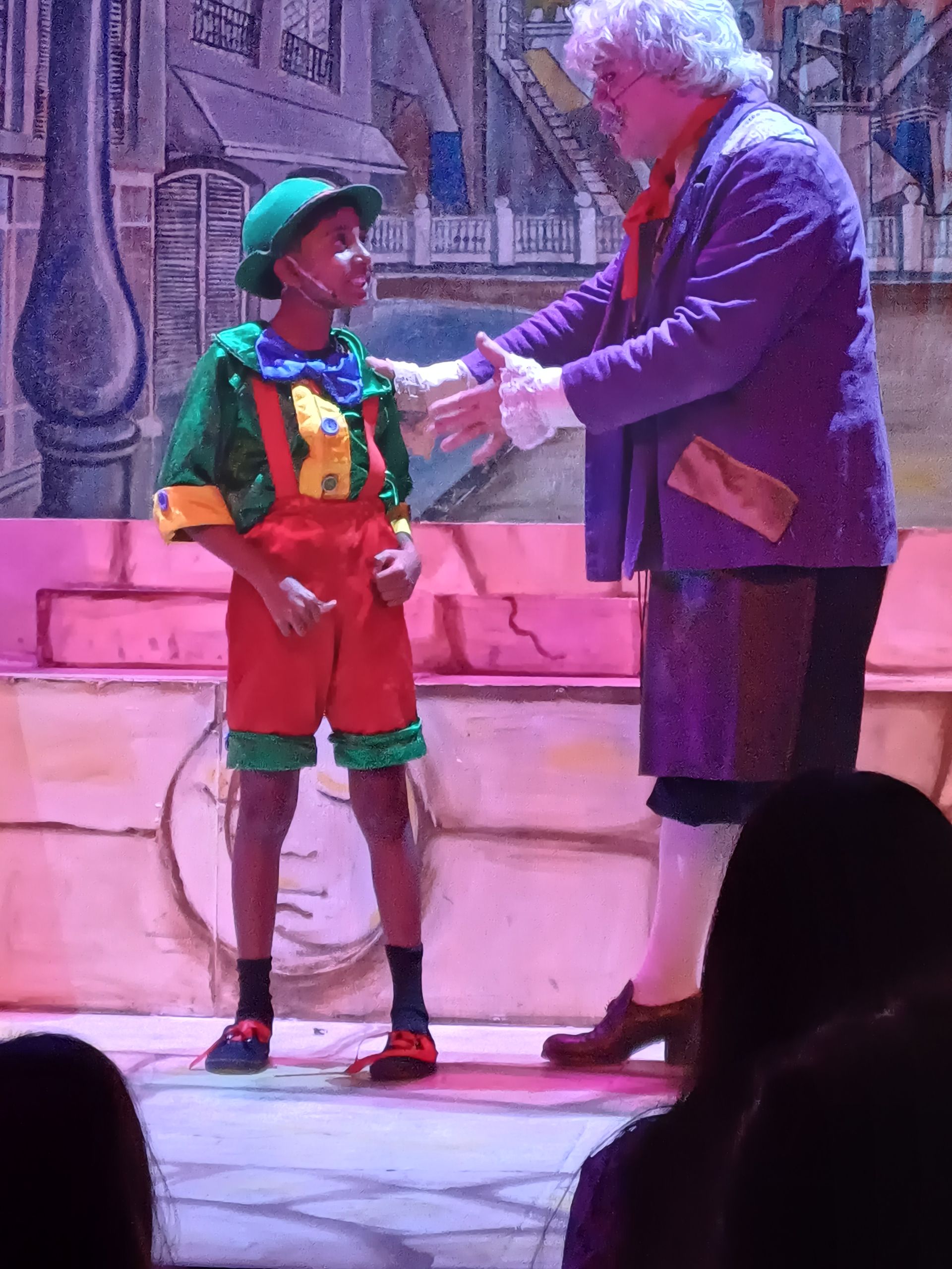 A man in a purple suit is talking to a boy in a green hat