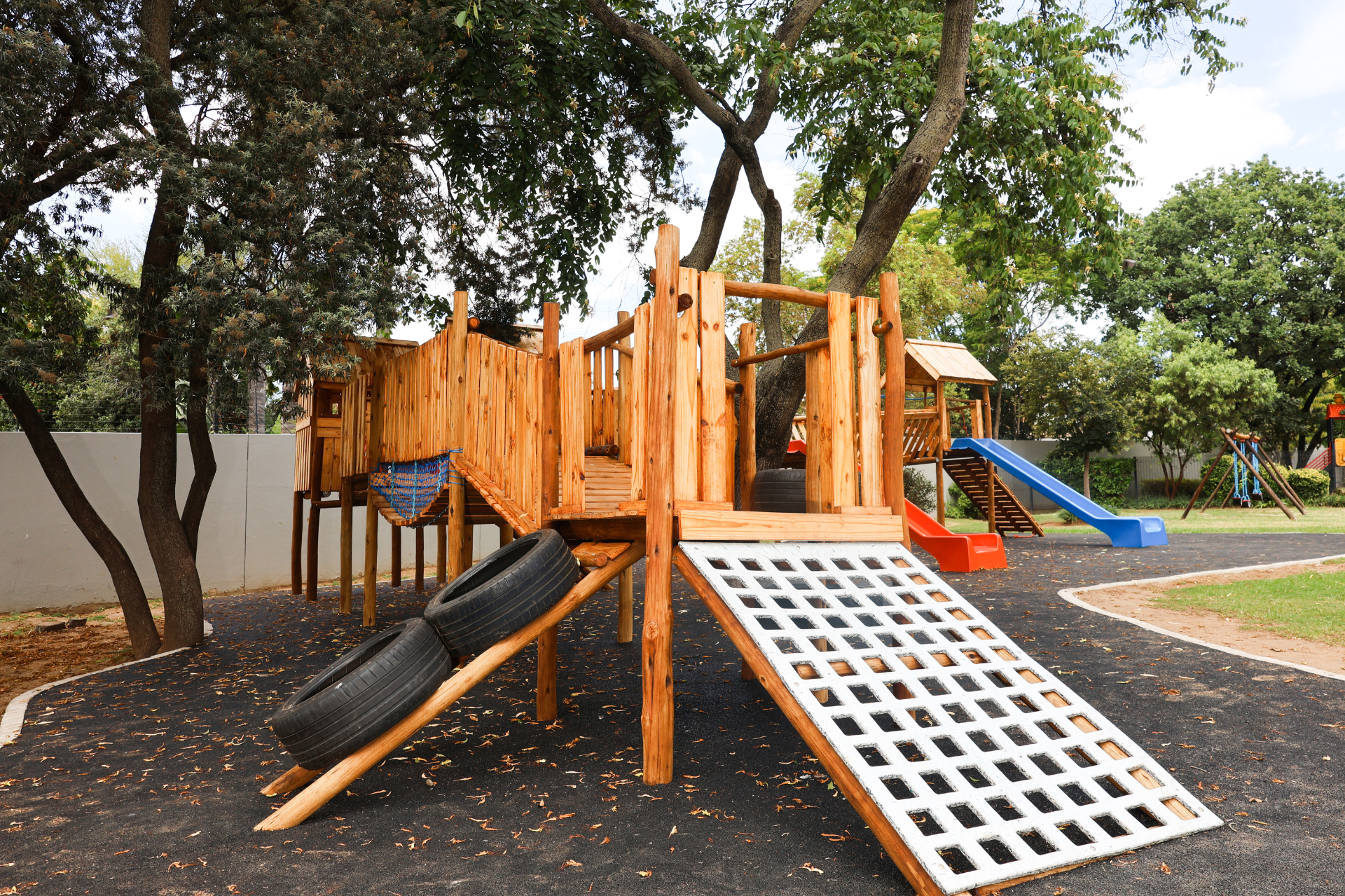 a wooden playground with a green slide and a red slide
