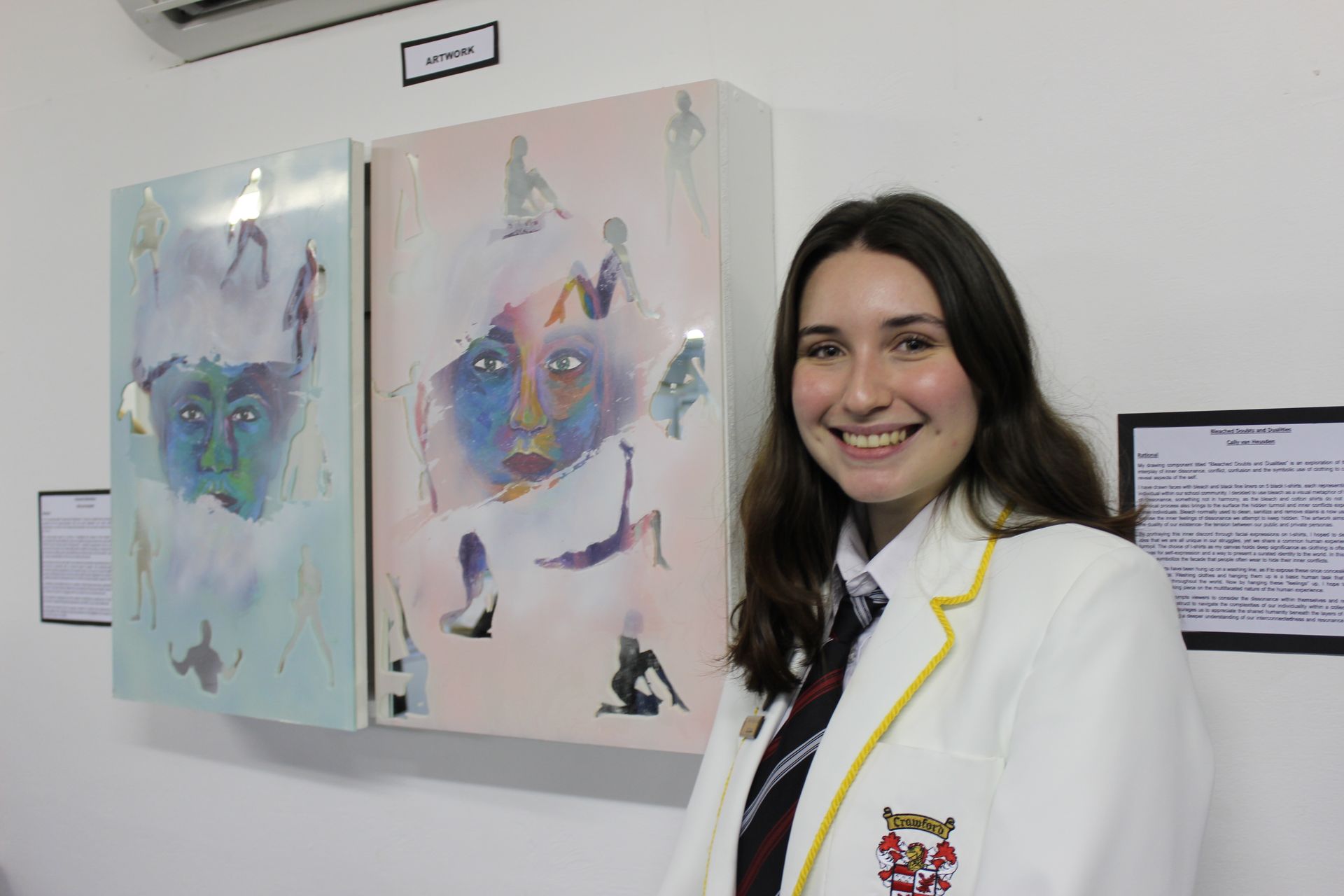 A young woman is standing in front of two paintings on a wall.