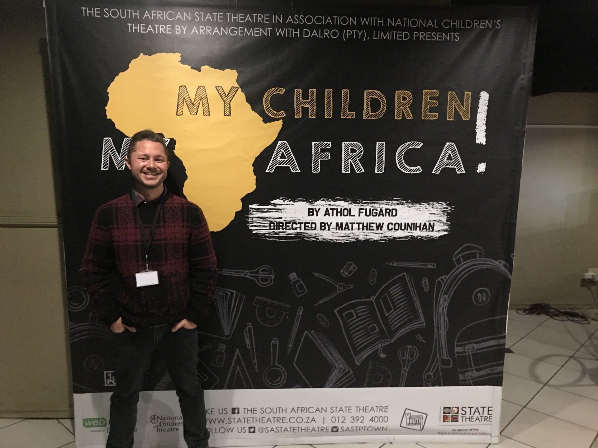A man is standing in front of a sign that says my children in africa
