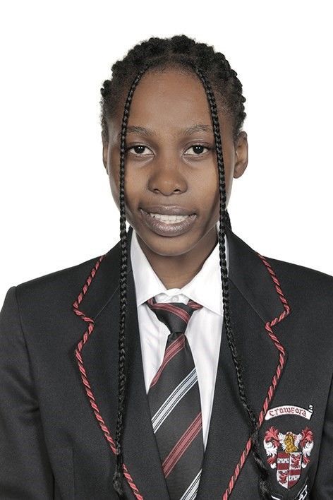 A girl wearing a suit and tie with a crest on the pocket