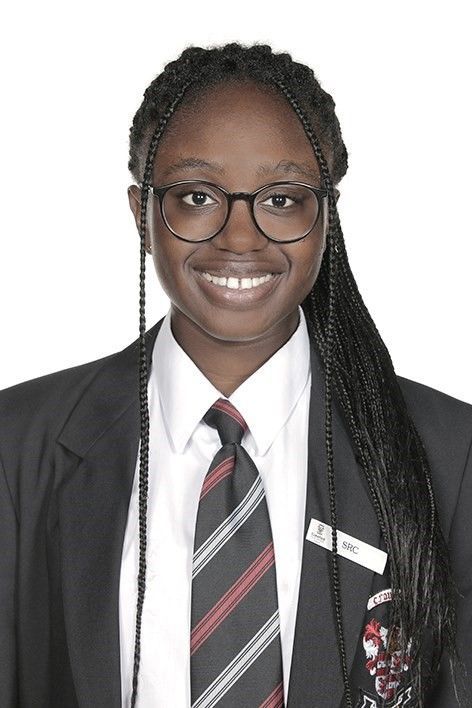 A young woman wearing a suit and tie is smiling for the camera.