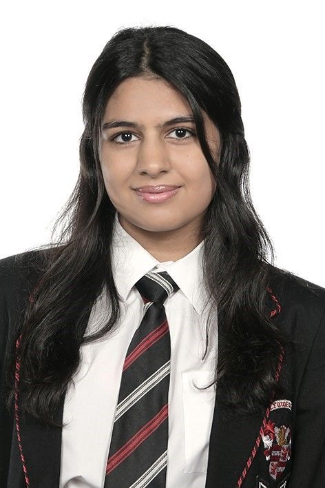 A young woman wearing a suit and tie is smiling for the camera.