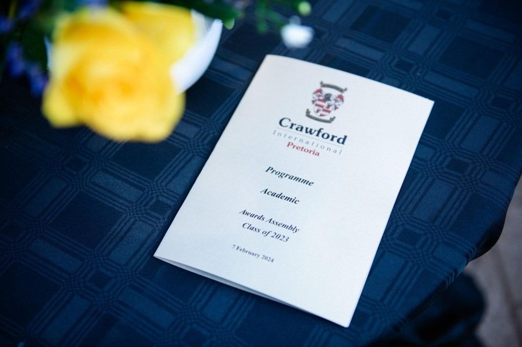 A crawford program is sitting on a table next to a yellow flower