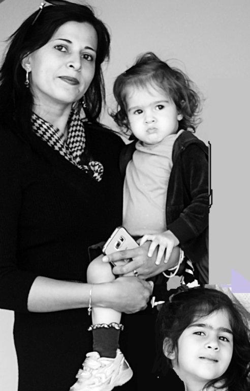A woman is holding two little girls in her arms