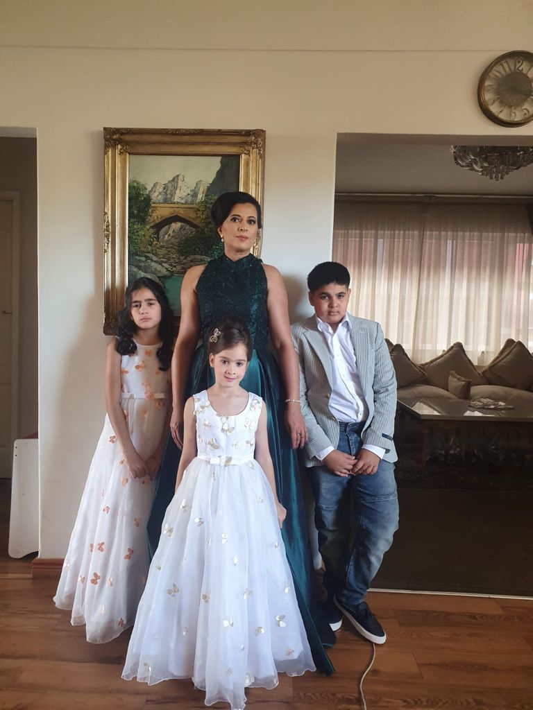 A woman and three children are posing for a picture in a living room.