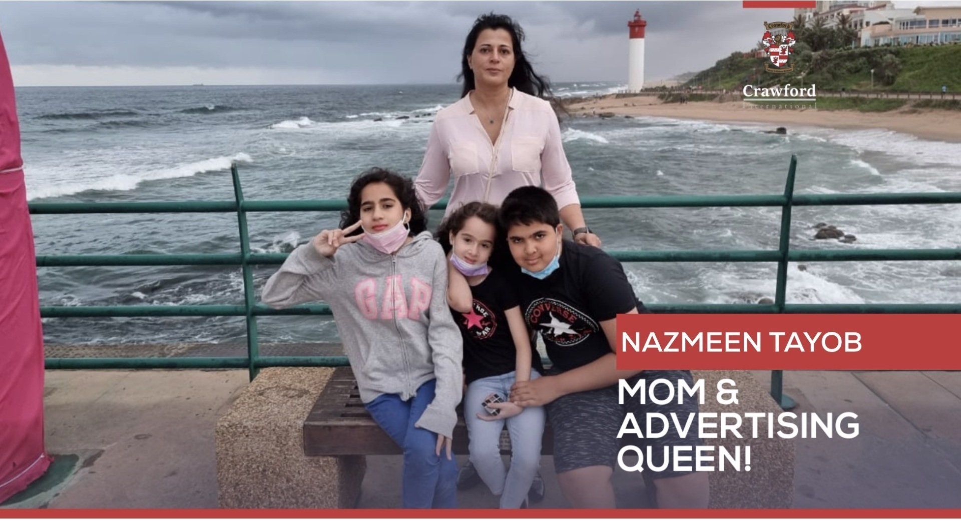 A woman and three children are sitting on a bench by the ocean.