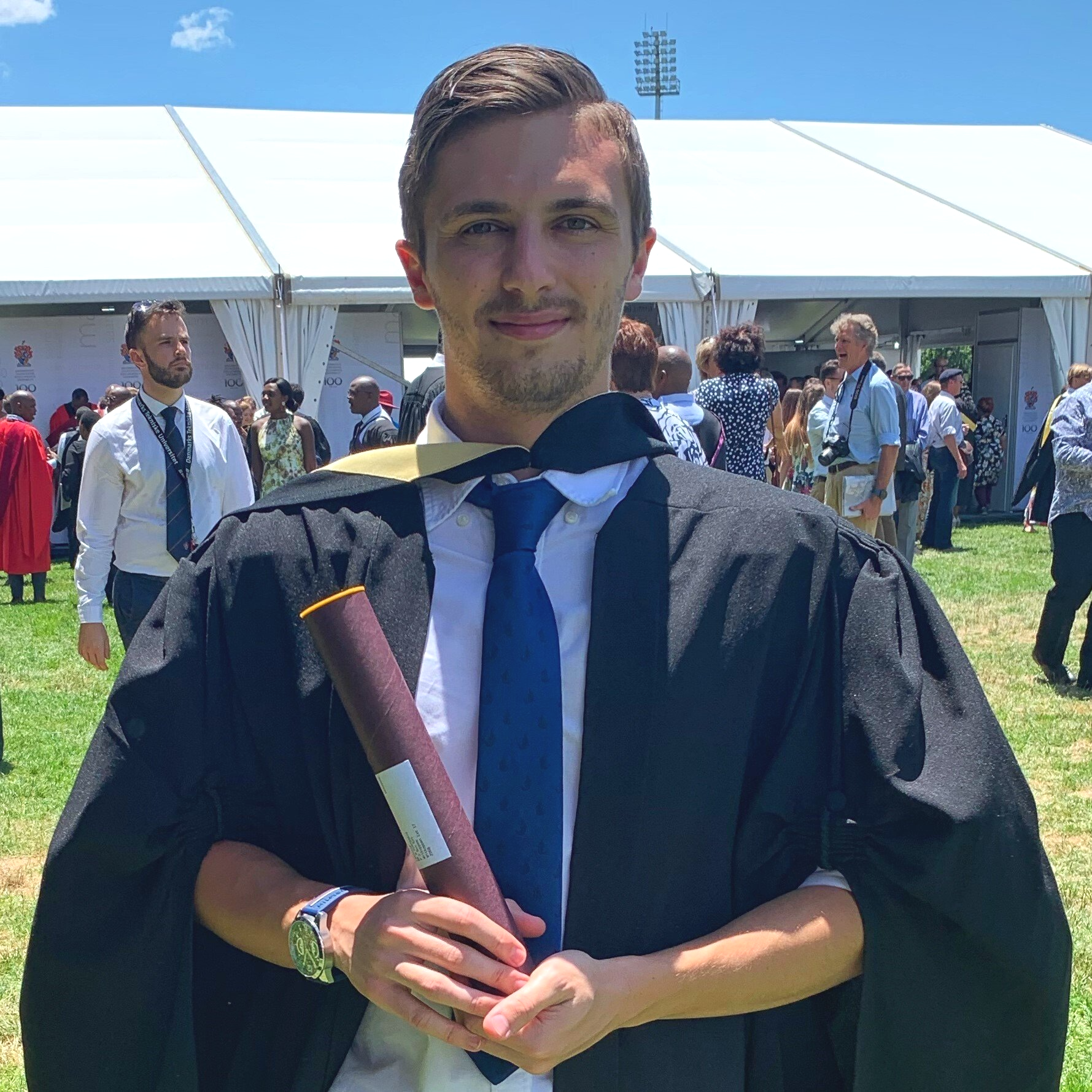 A man in a graduation cap and gown is holding a diploma.