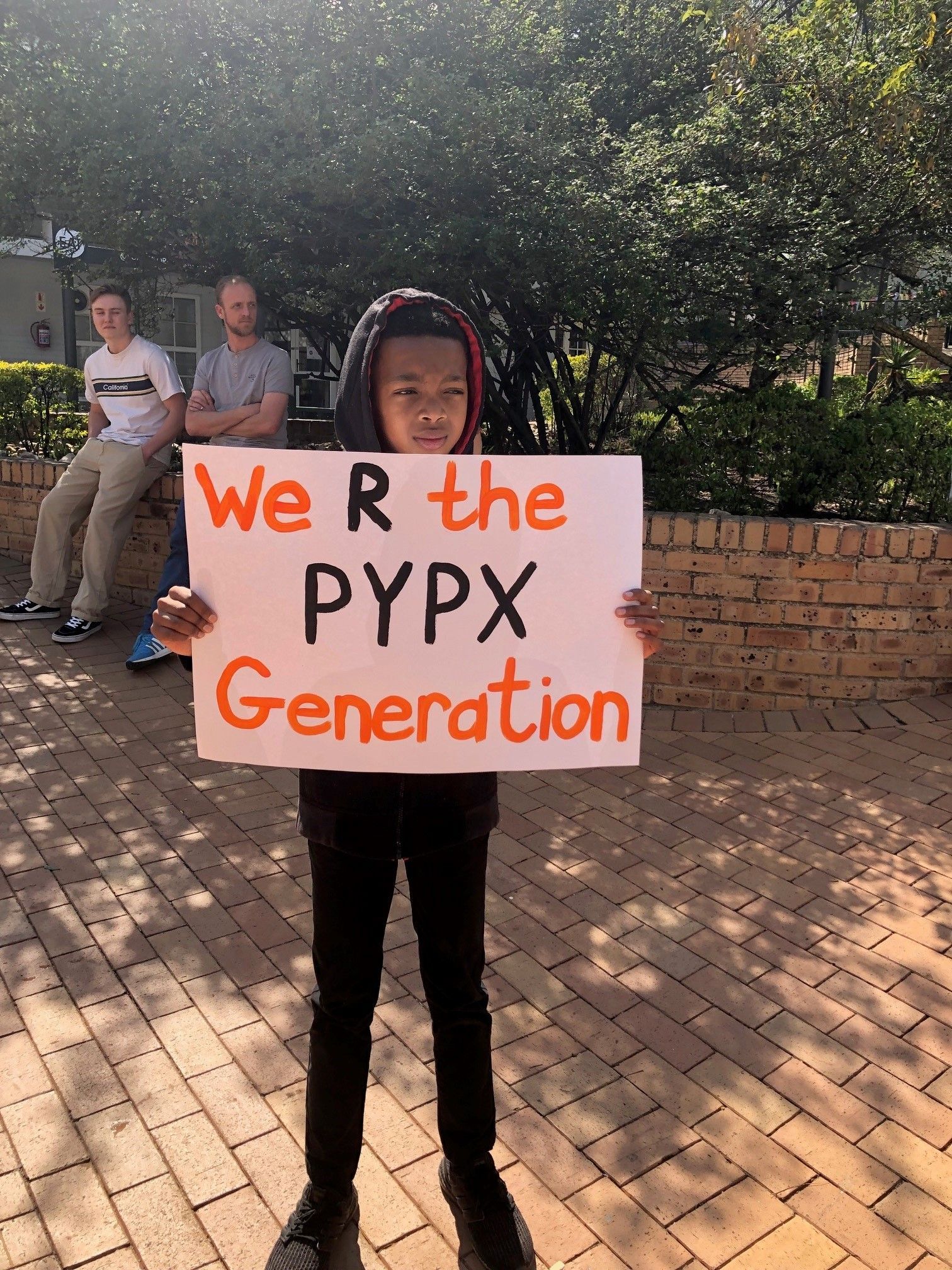 A young boy is holding a sign that says we r the pypx generation