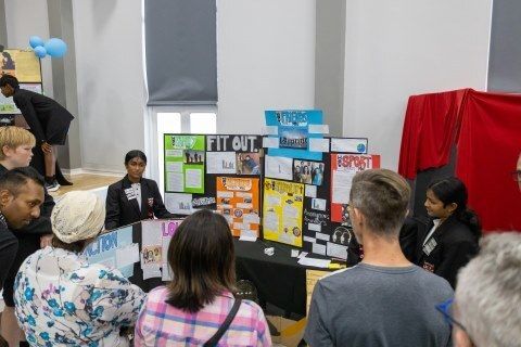 A group of people are standing around a table with posters on it.