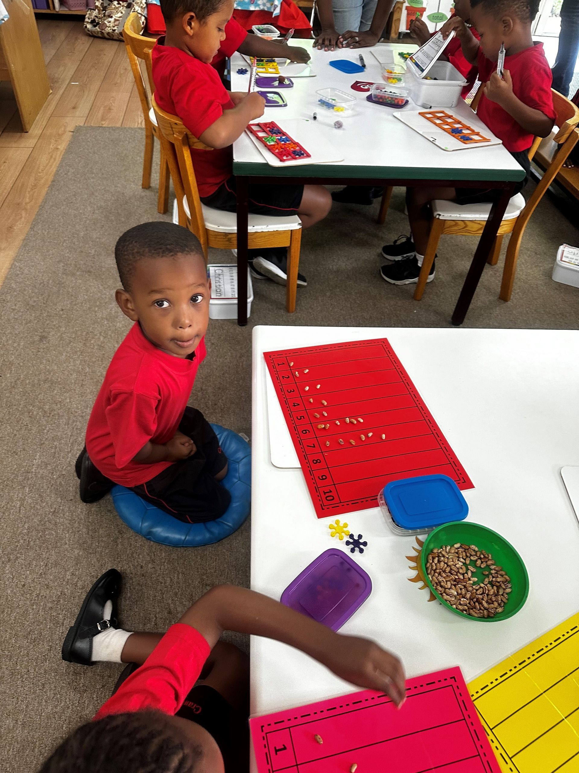 A group of children are sitting at tables in a classroom