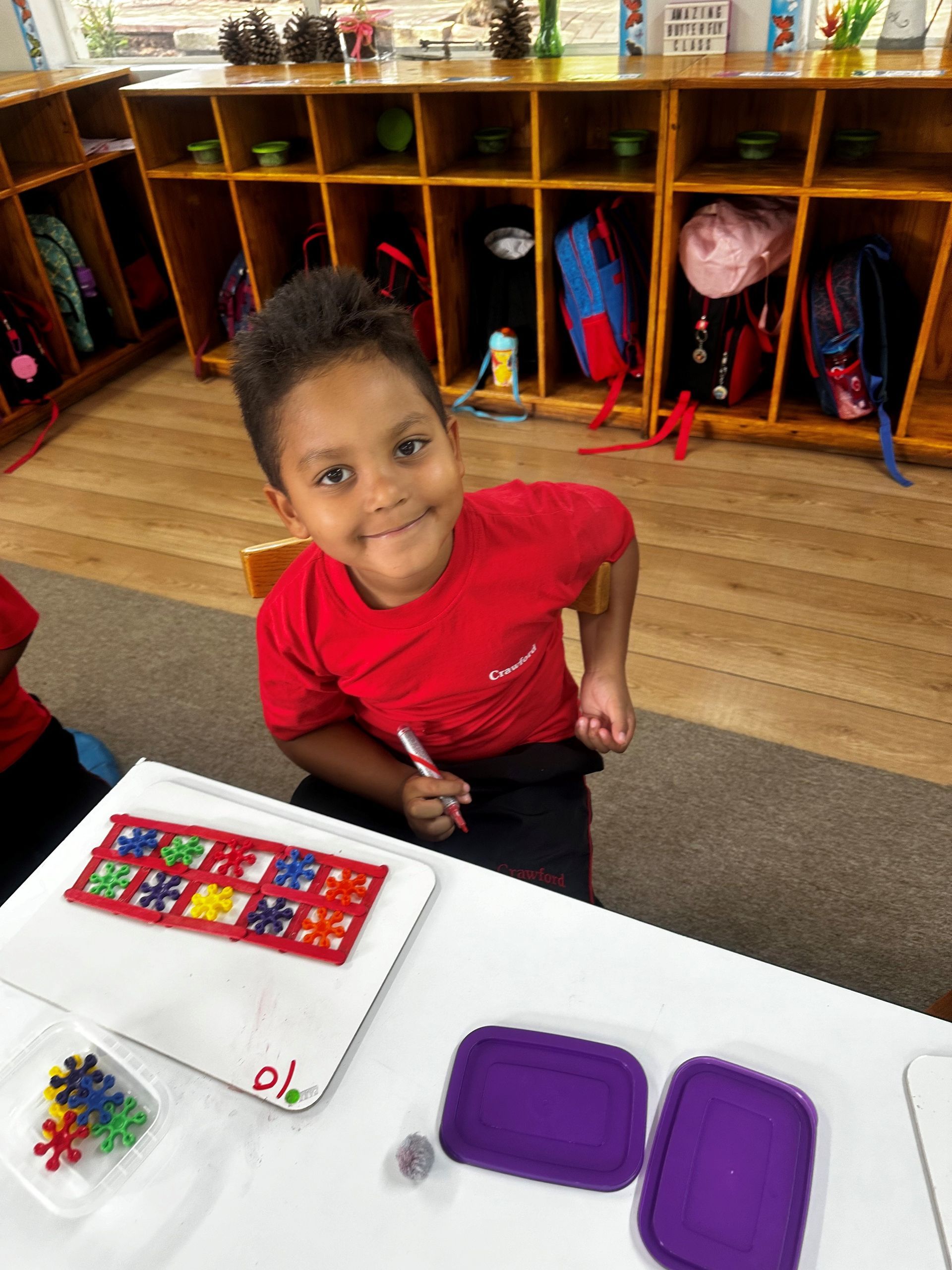A young boy in a red shirt is sitting at a table