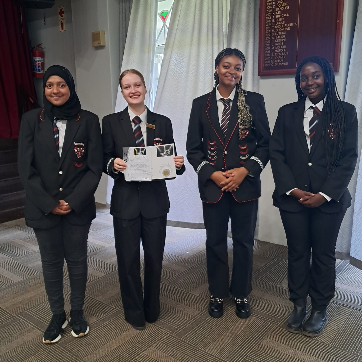 Four women in suits and ties are standing next to each other
