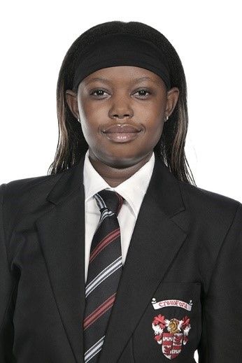 A woman wearing a suit and tie with a crest on the pocket