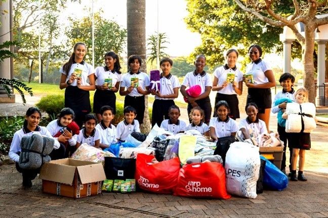 A group of children are posing for a picture with bags of clothes.