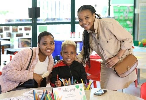 A woman and two children are posing for a picture in a classroom.
