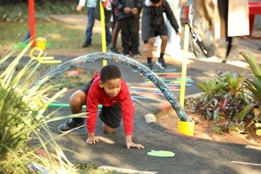 A young boy is crawling over a hose on a playground.