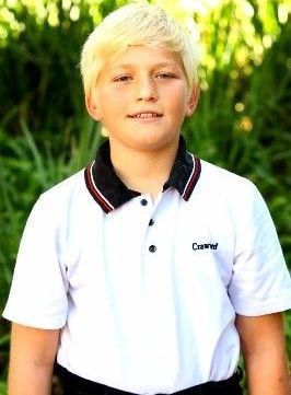 A young boy wearing a white polo shirt with the word cherry on it