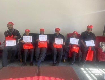 A group of people are sitting on a couch holding certificates.