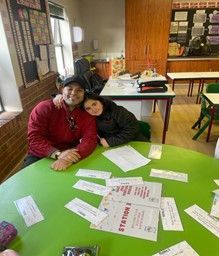 A man and a woman are sitting at a table in a classroom.