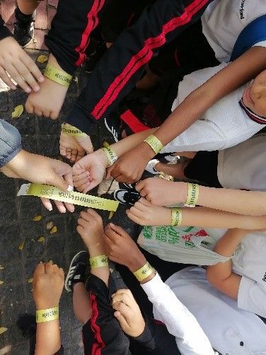 A group of children are putting their hands together with bracelets on their wrists