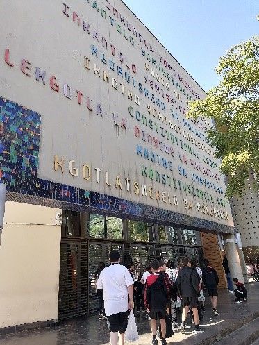 A group of people are walking in front of a building with a large sign on it.