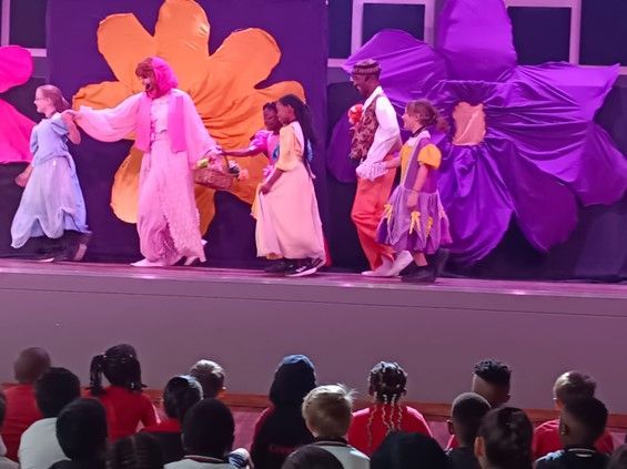 A group of children are watching a performance on stage