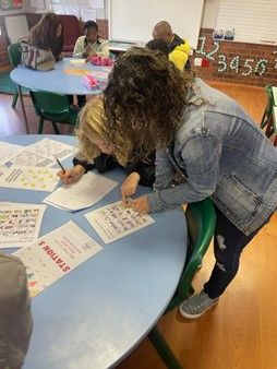 A group of people are sitting at a table writing on papers.