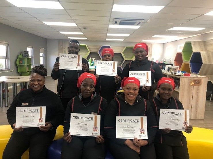 A group of people are holding certificates in a room.