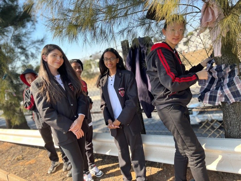 A group of young people are standing next to a tree.