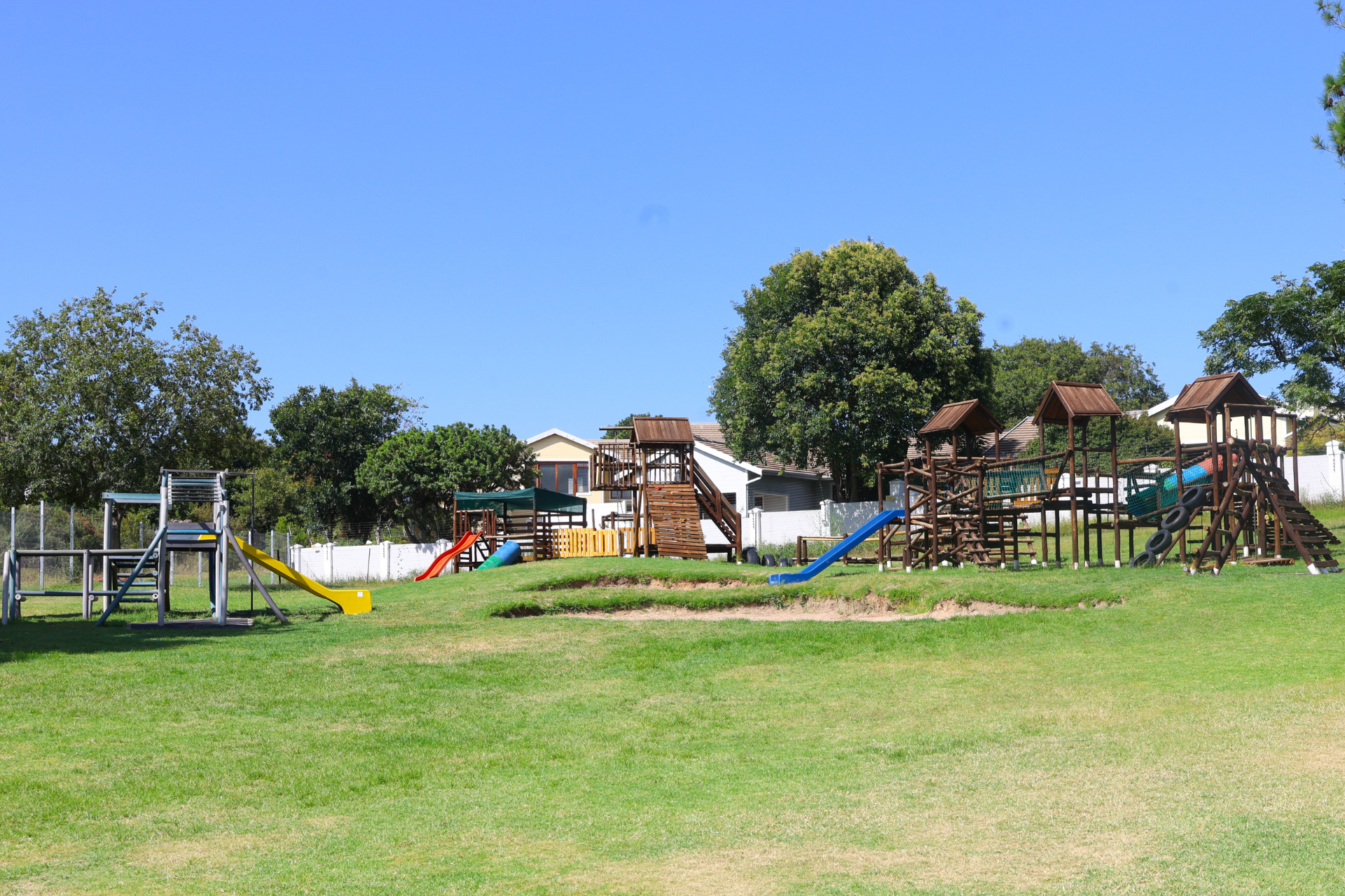 A playground with a red slide and a wooden house