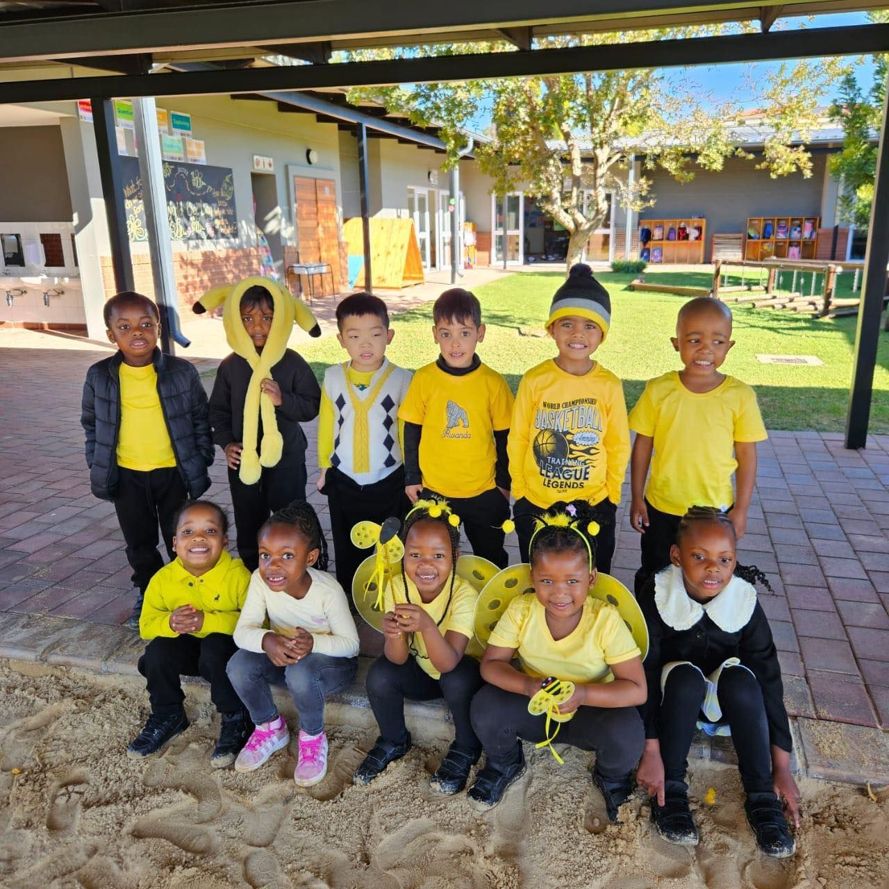 Group of children in yellow clothing posing outdoors.