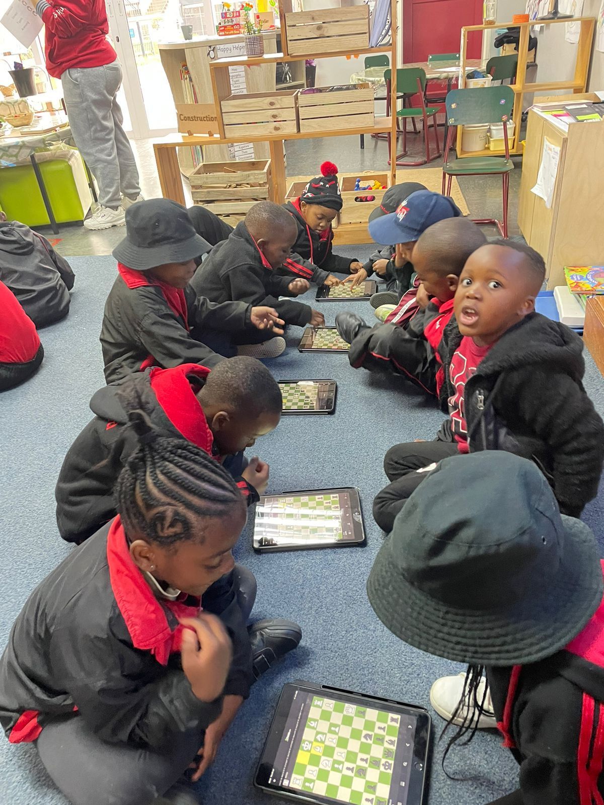 A group of children are sitting on the floor playing chess.
