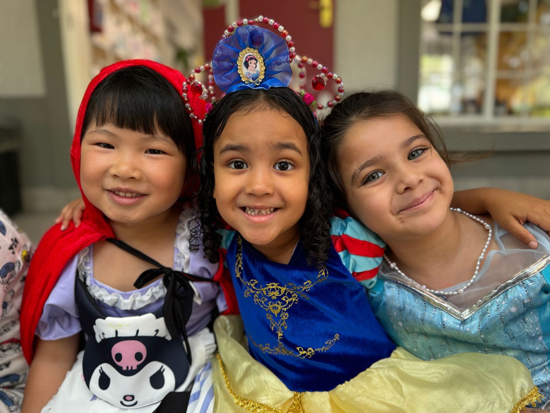 Three little girls dressed in costumes are posing for a picture.